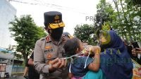 Kapolda Jatim Bagikan Beras dan Kenakan Masker Kepada Anak Kecil yang Tak Bermasker
